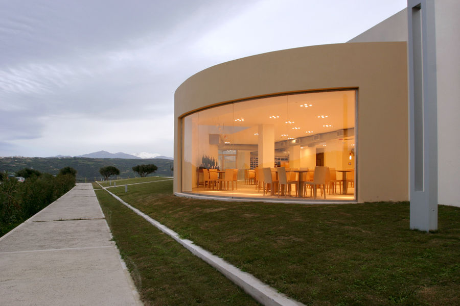 one side of the building with green lawn of Boutari Crete Winery next to the vineyards